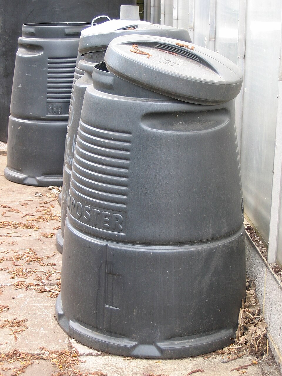 A black domestic compost bin in a garden