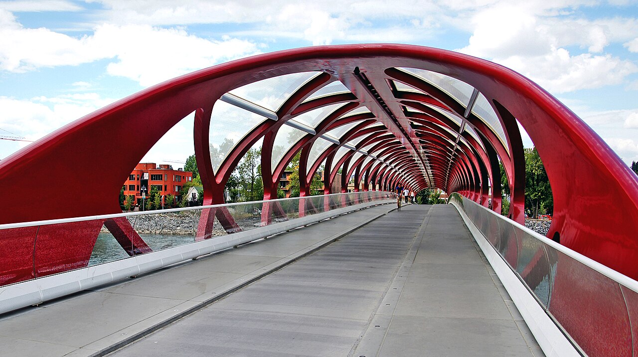 Cyclists crossing a red arched cycle and pedestrian bridge