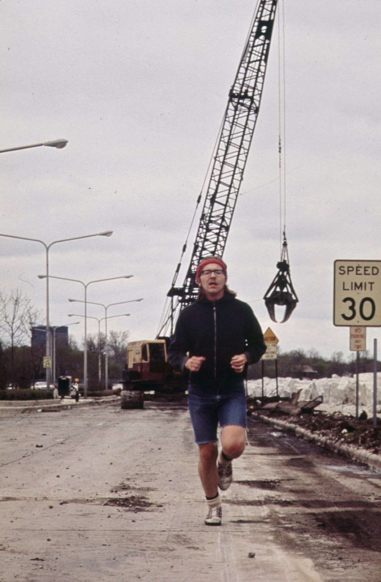 JOGGING ALONG LAKE MICHIGAN IN EVANSTON. CRANE IN BACKGROUND IS REPAIRING STORM DAMAGE - NARA - 547074