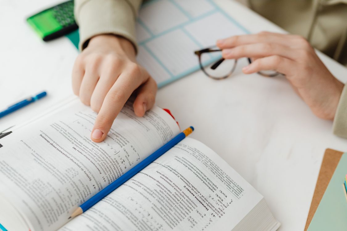 A close-up of a student studying math with a textbook and pencil at a desk