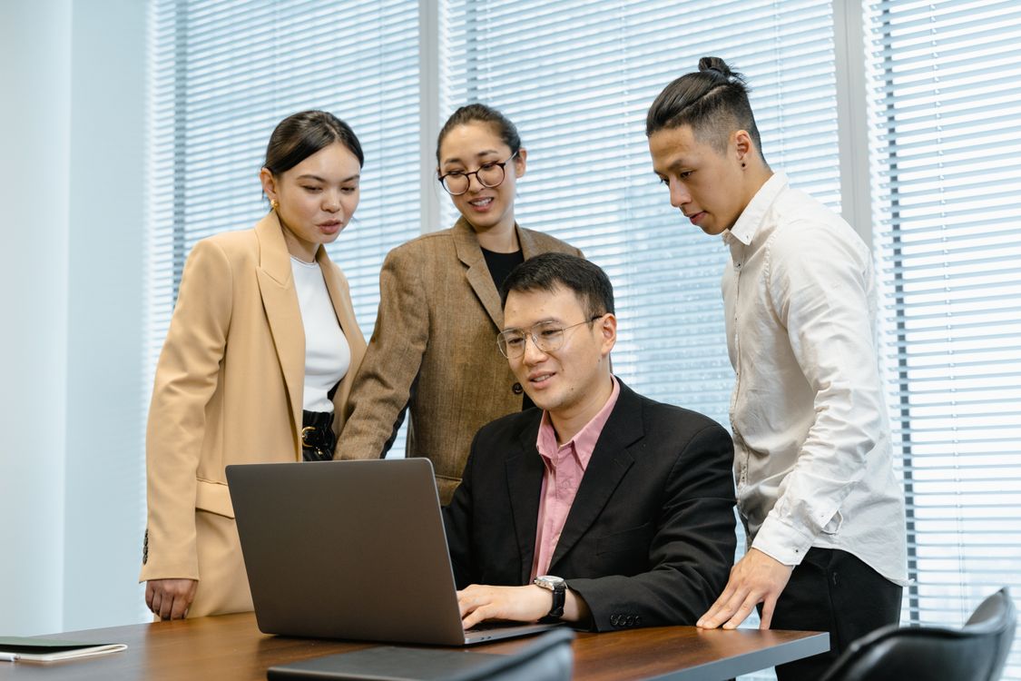 Four colleagues talking around a laptop in an office