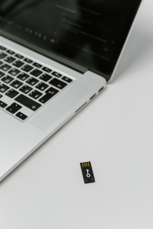 A USB security key beside a laptop, showing a physical second factor for login
