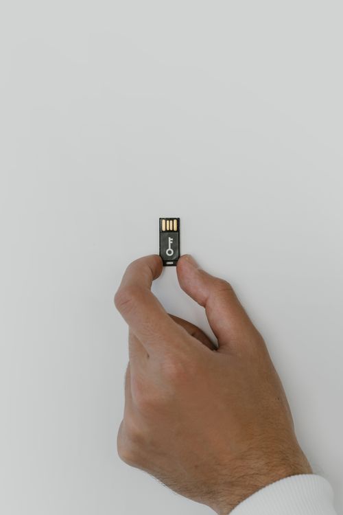 A hand holds a security-themed USB flash drive against a white backdrop