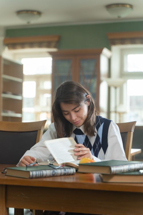 A young student reading at a library, surrounded by books
