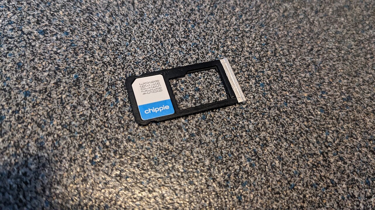 A nano SIM card held beside its packaging