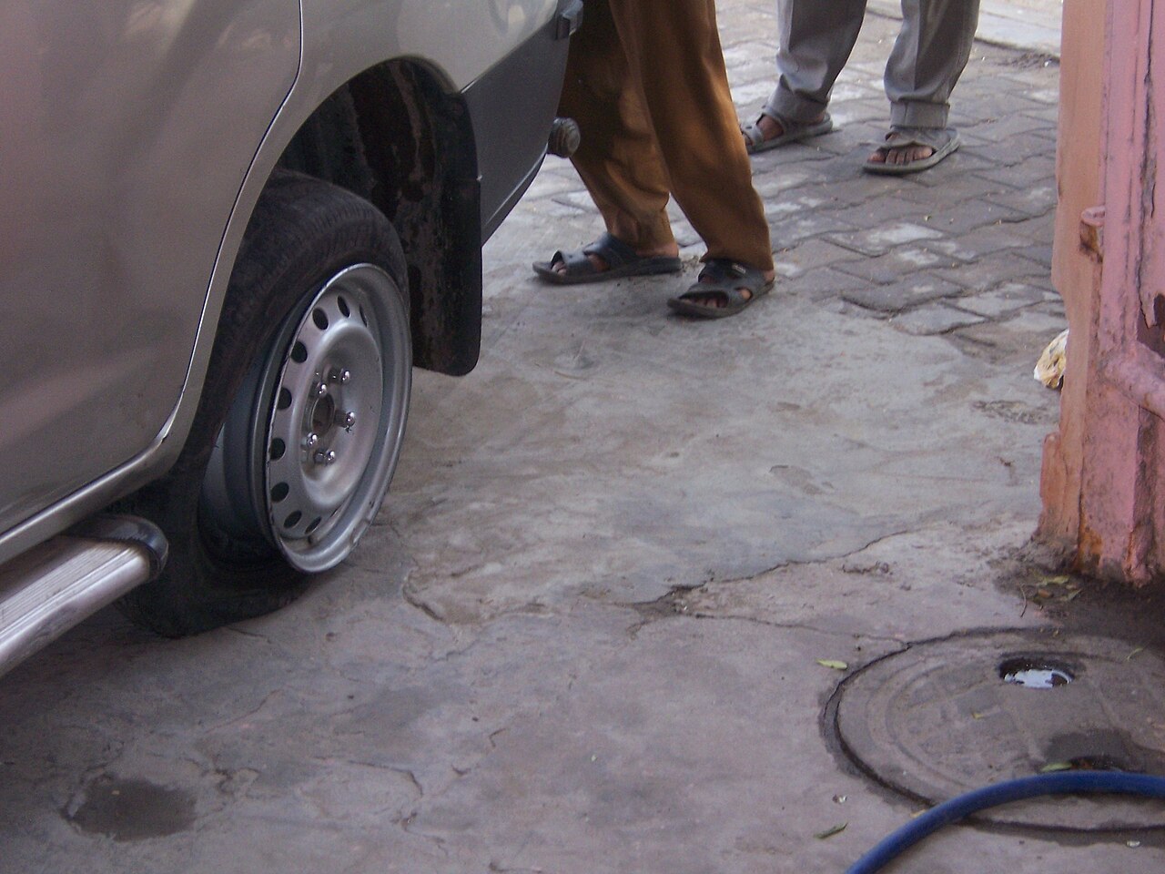 A car with a flat tyre parked on a paved surface