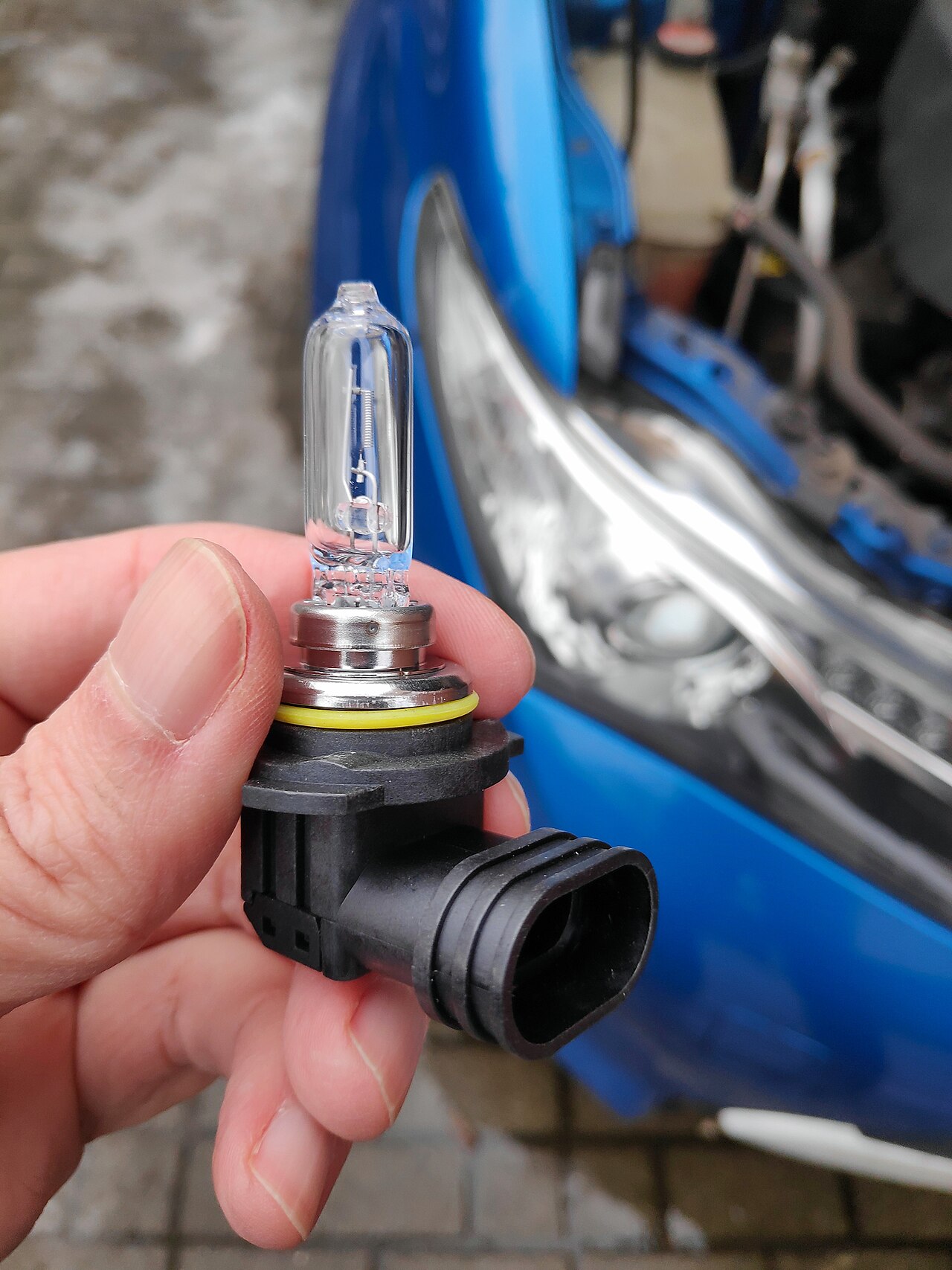 A car headlight with a bulb being replaced, showing the clear lens housing