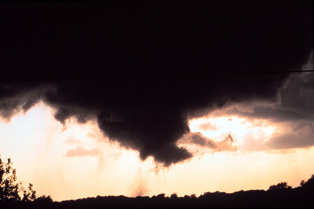 A backlit funnel cloud and tornado photographed against a dark sky