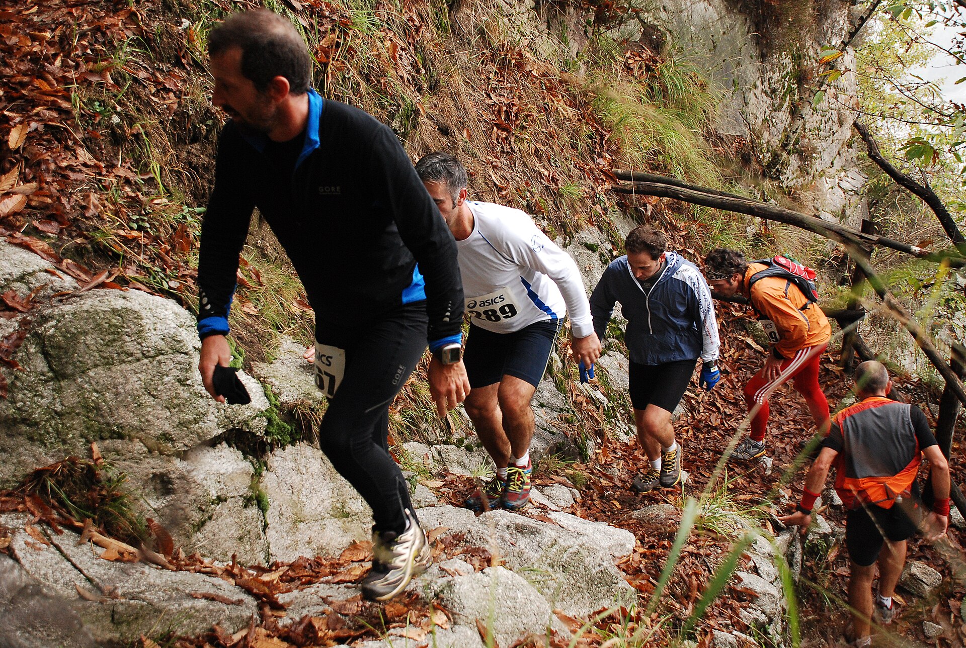A trail runner on a mountain path above a lake