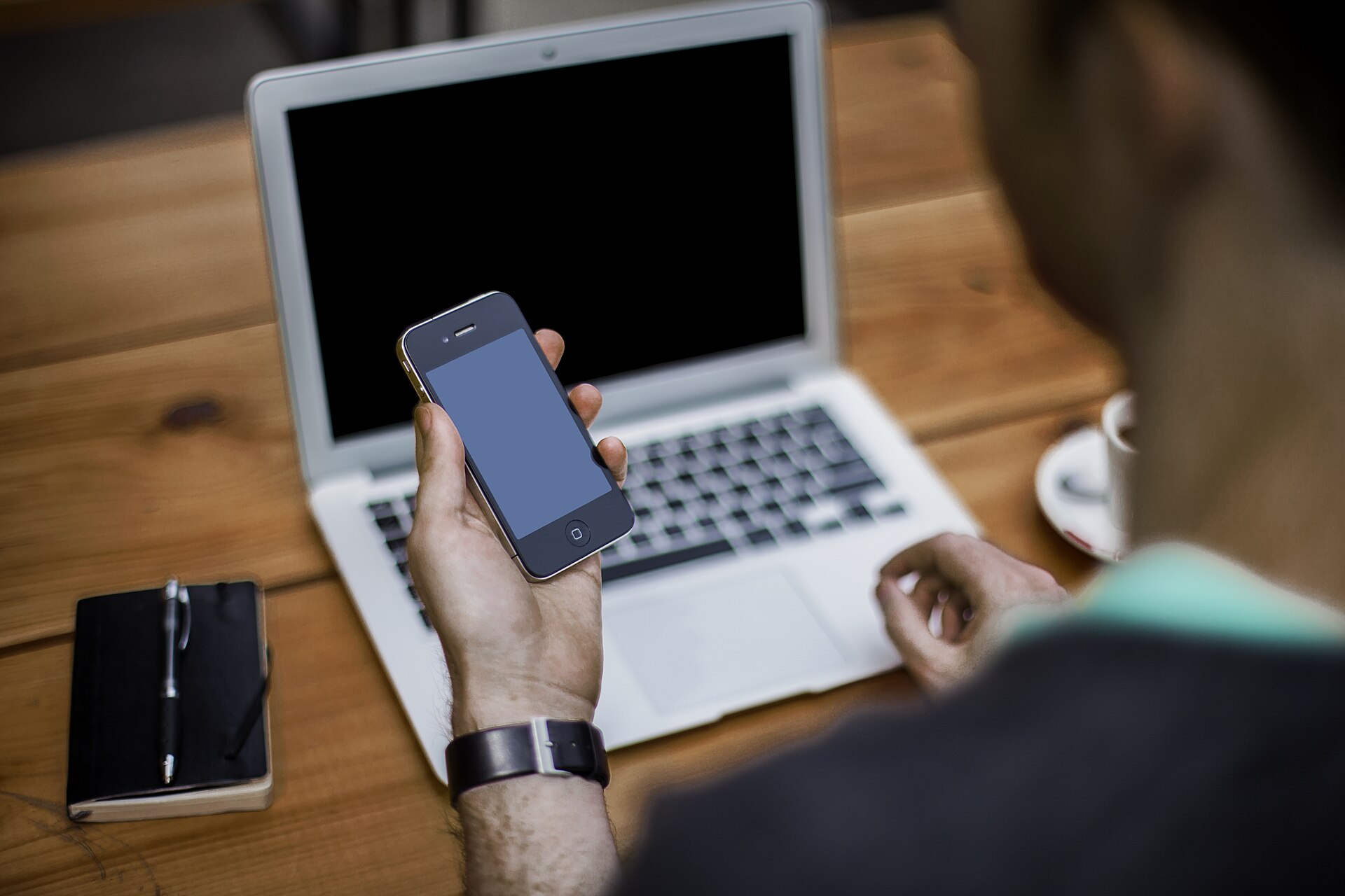 A man using a smartphone with a laptop nearby