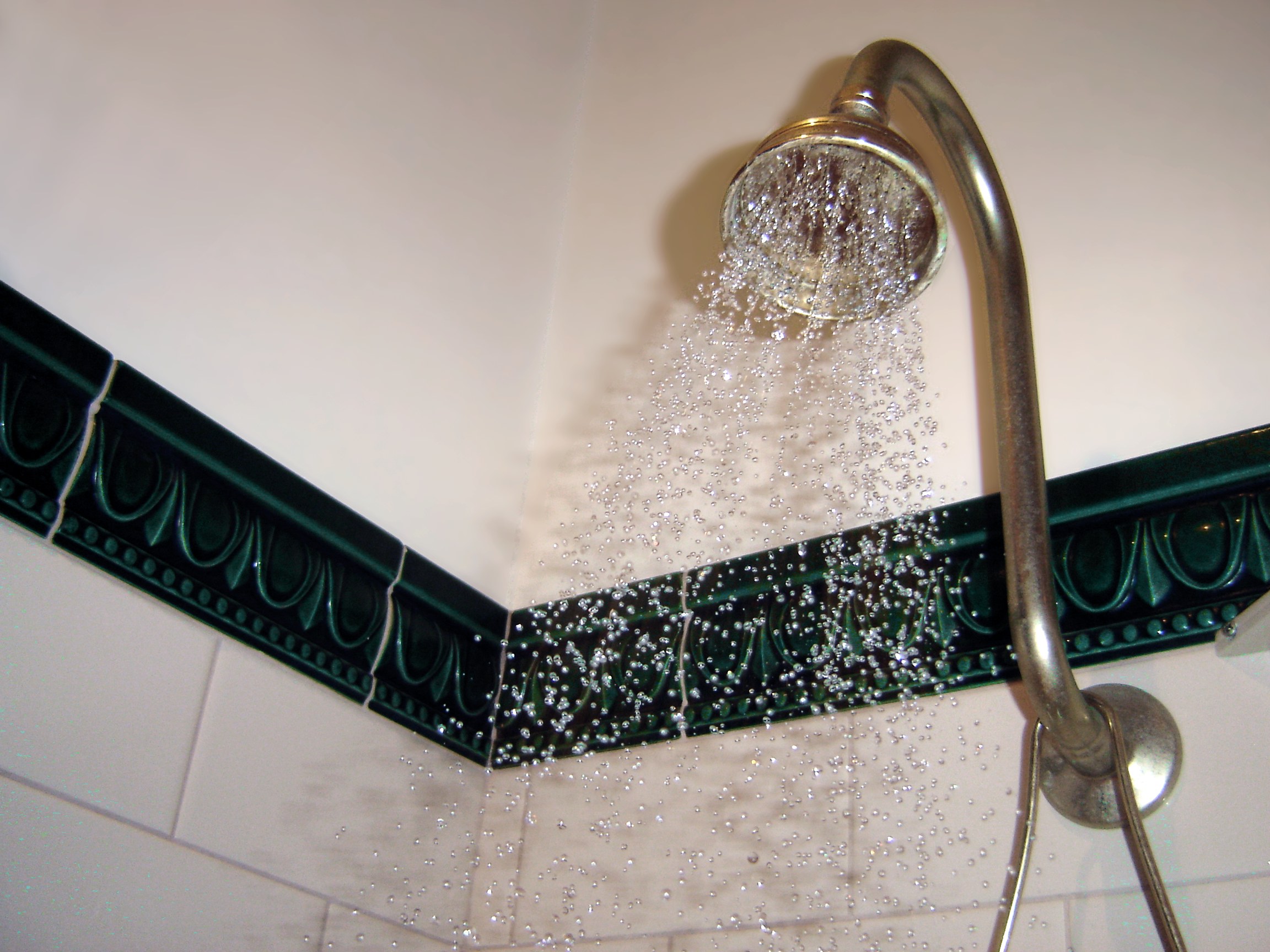 A chrome shower head mounted on a tiled bathroom wall