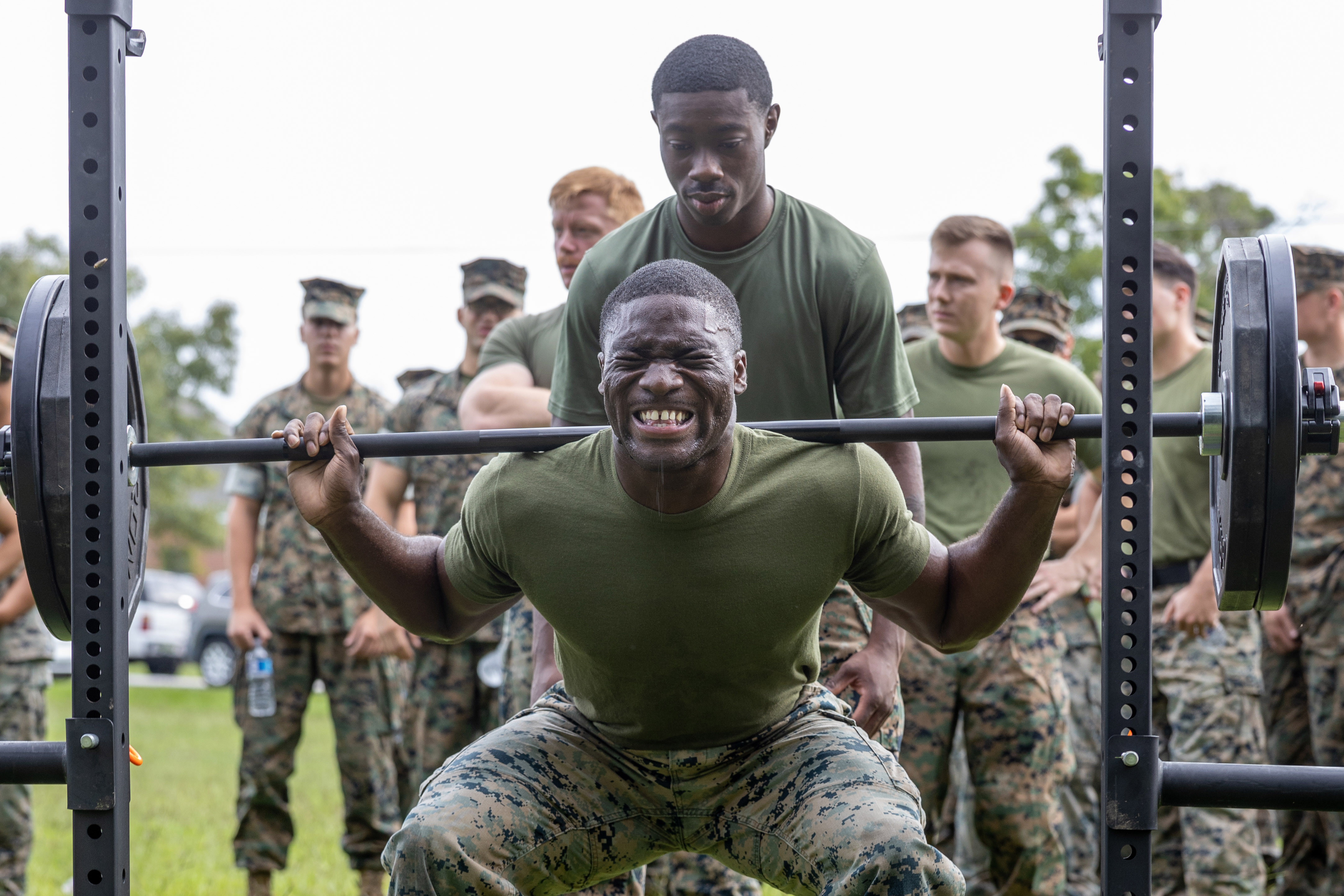 A service member doing barbell squats during training