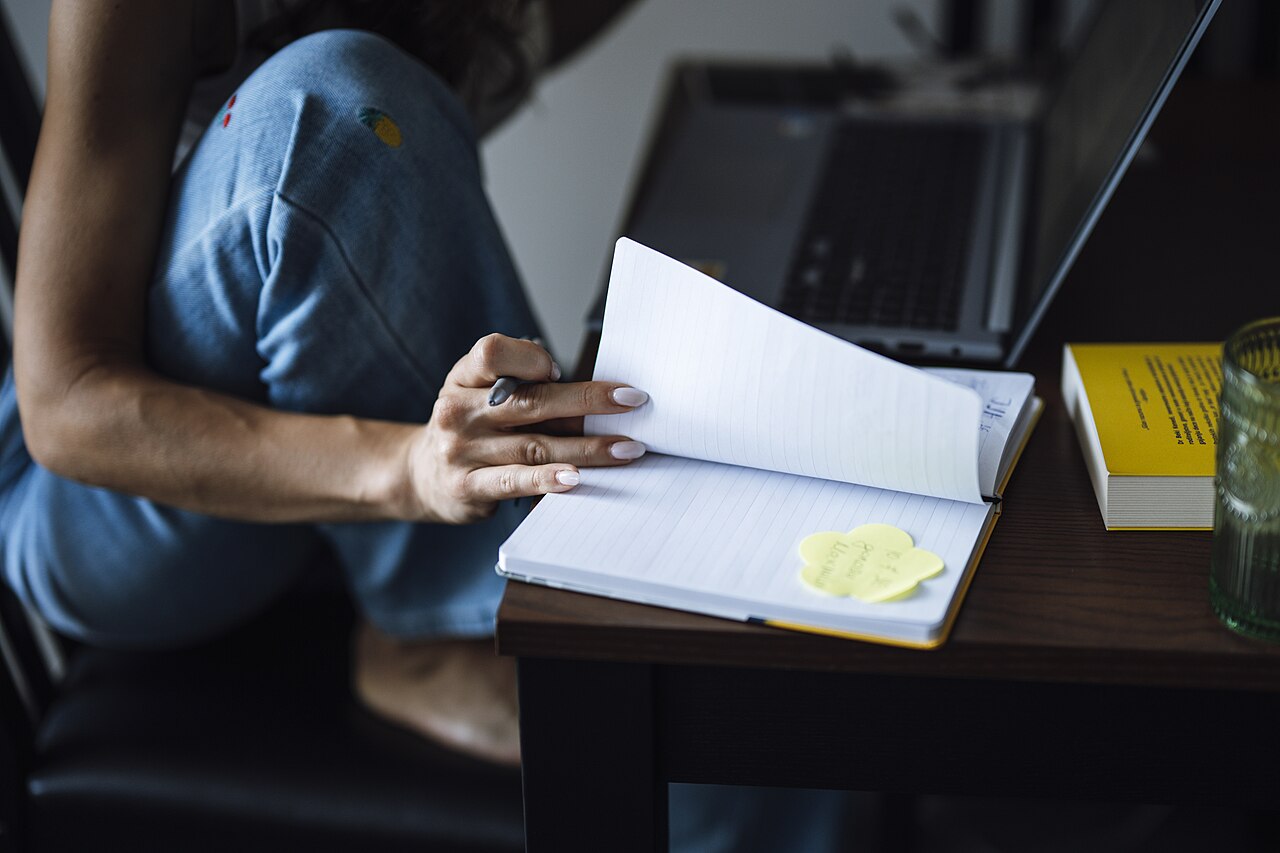 A person writing notes in a notebook at a table
