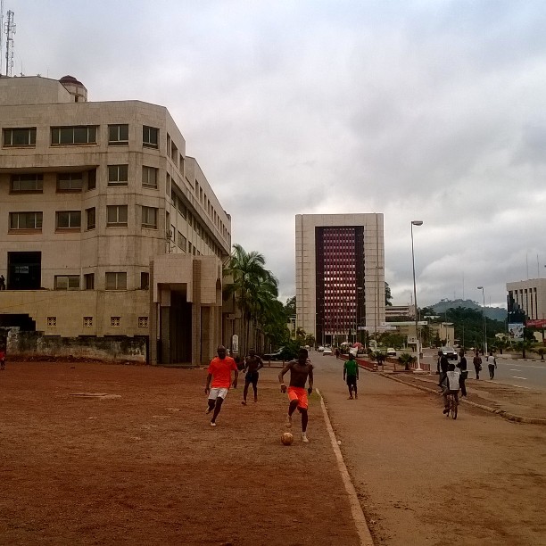 Players playing football on an open dirt lot in Yaounde