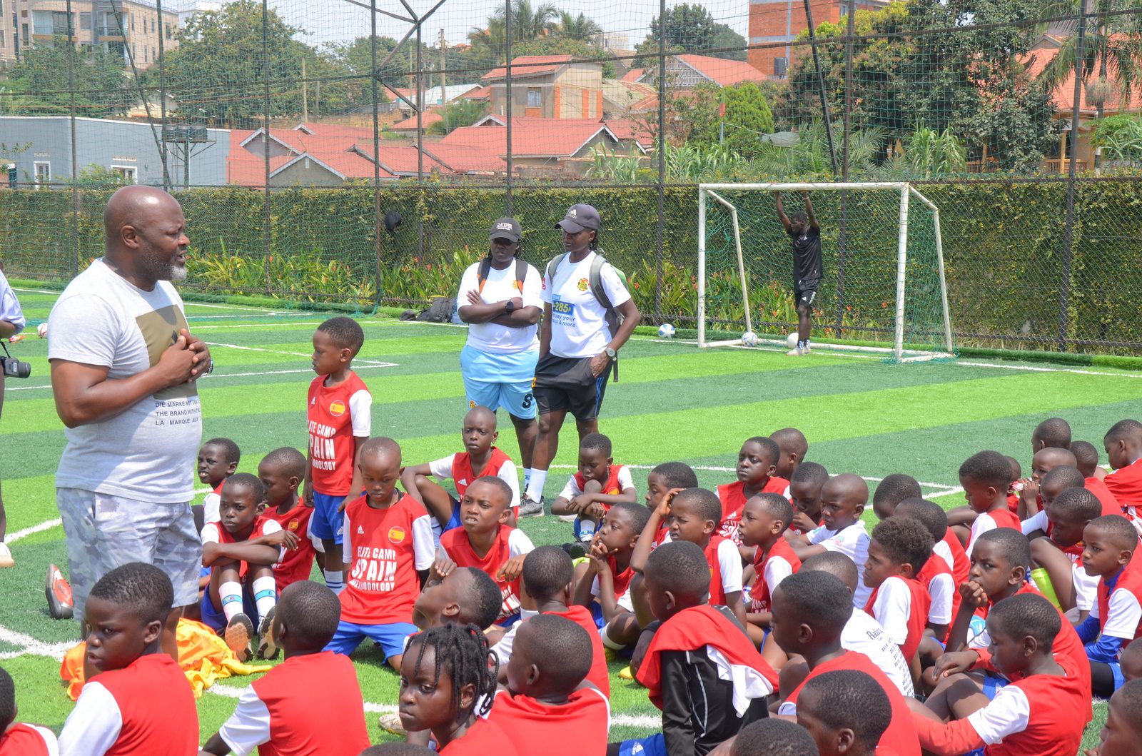 Young players sitting on a pitch listening to a coach at a soccer academy session