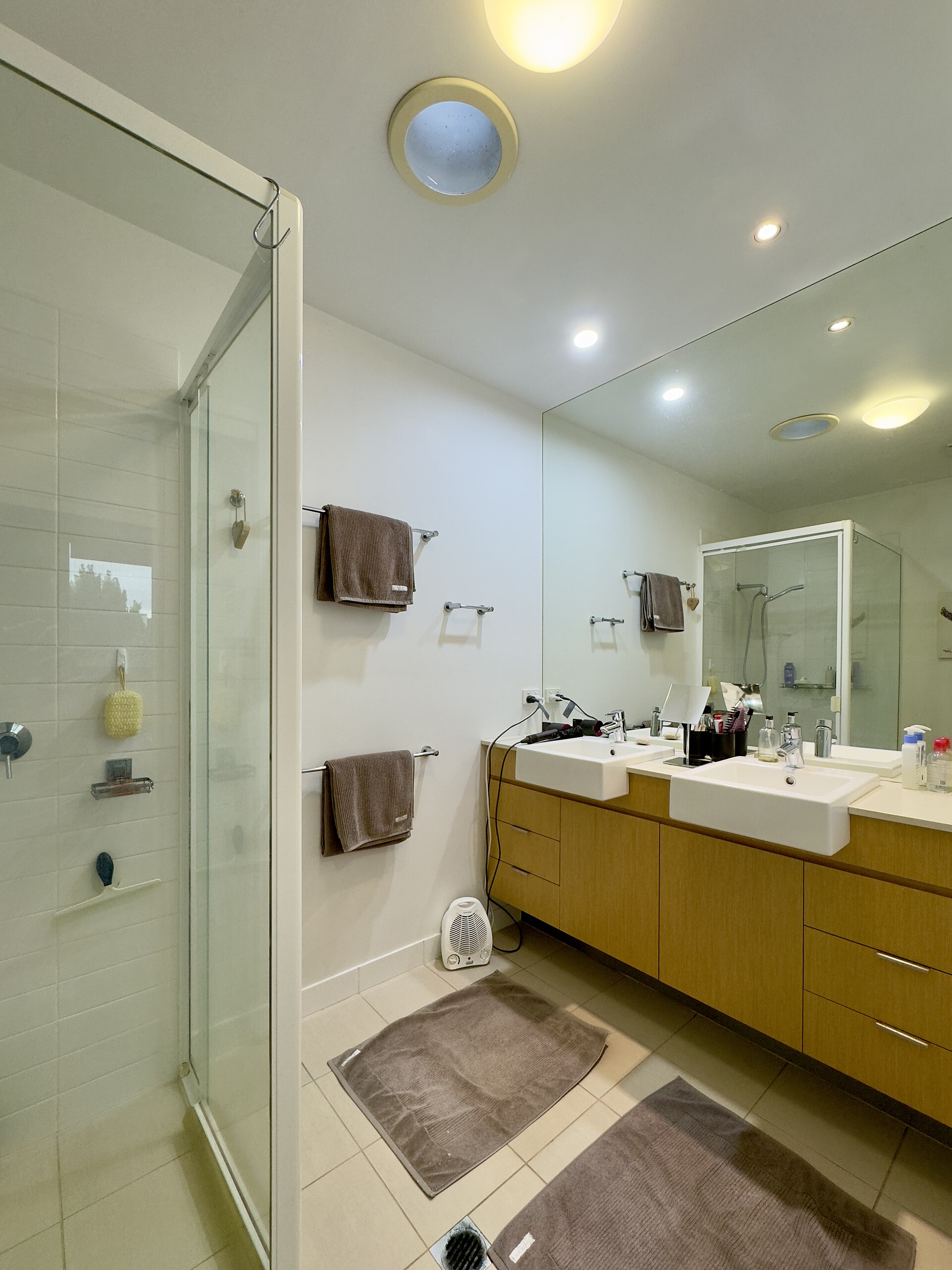 A bathroom with a glass shower and double sinks