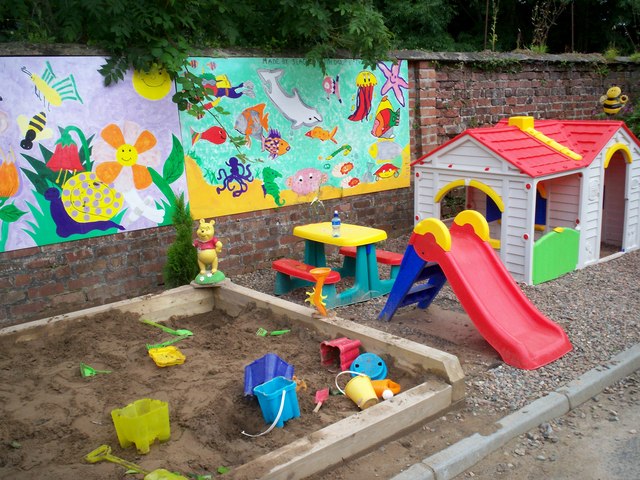 A toddler play area with a sandpit, slide, and playhouse