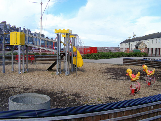 A playground with a slide and duck shaped spring riders