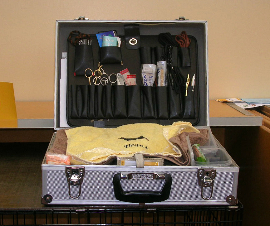 An open dog grooming kit with scissors, tools, and towels