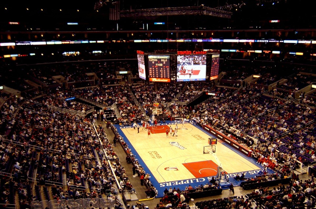 A basketball arena full of fans watching a game on the court