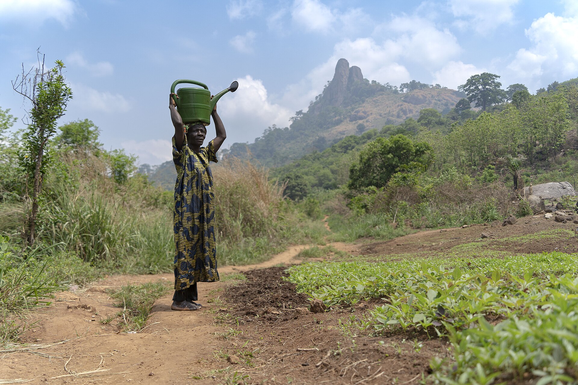 A woman holding a watering can in a garden