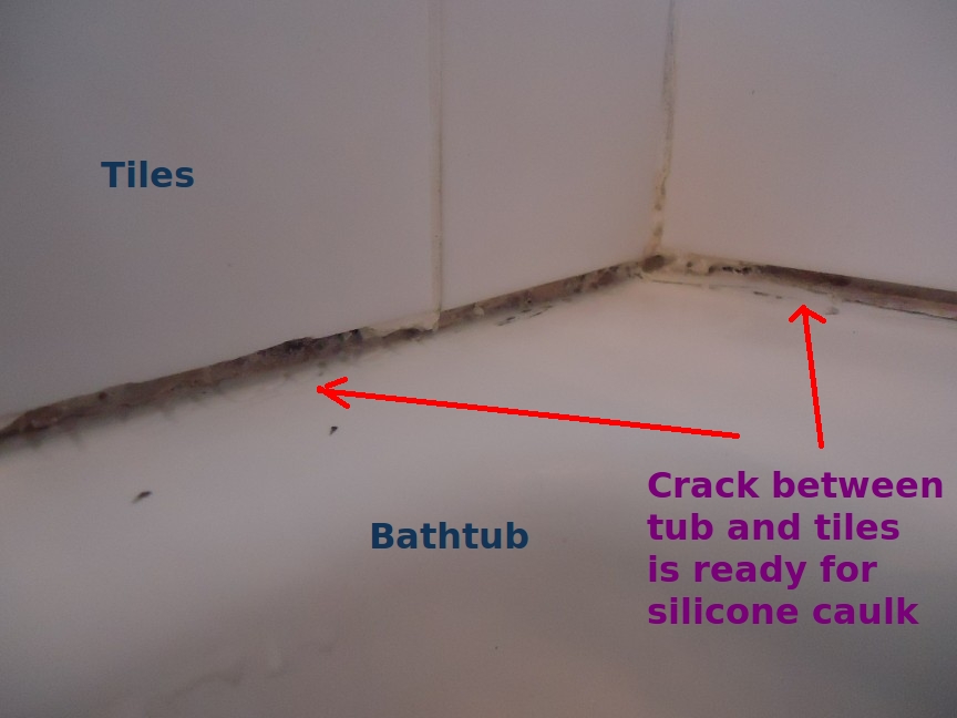 A gap between bathtub and tiles with old caulk removed, ready for new sealant
