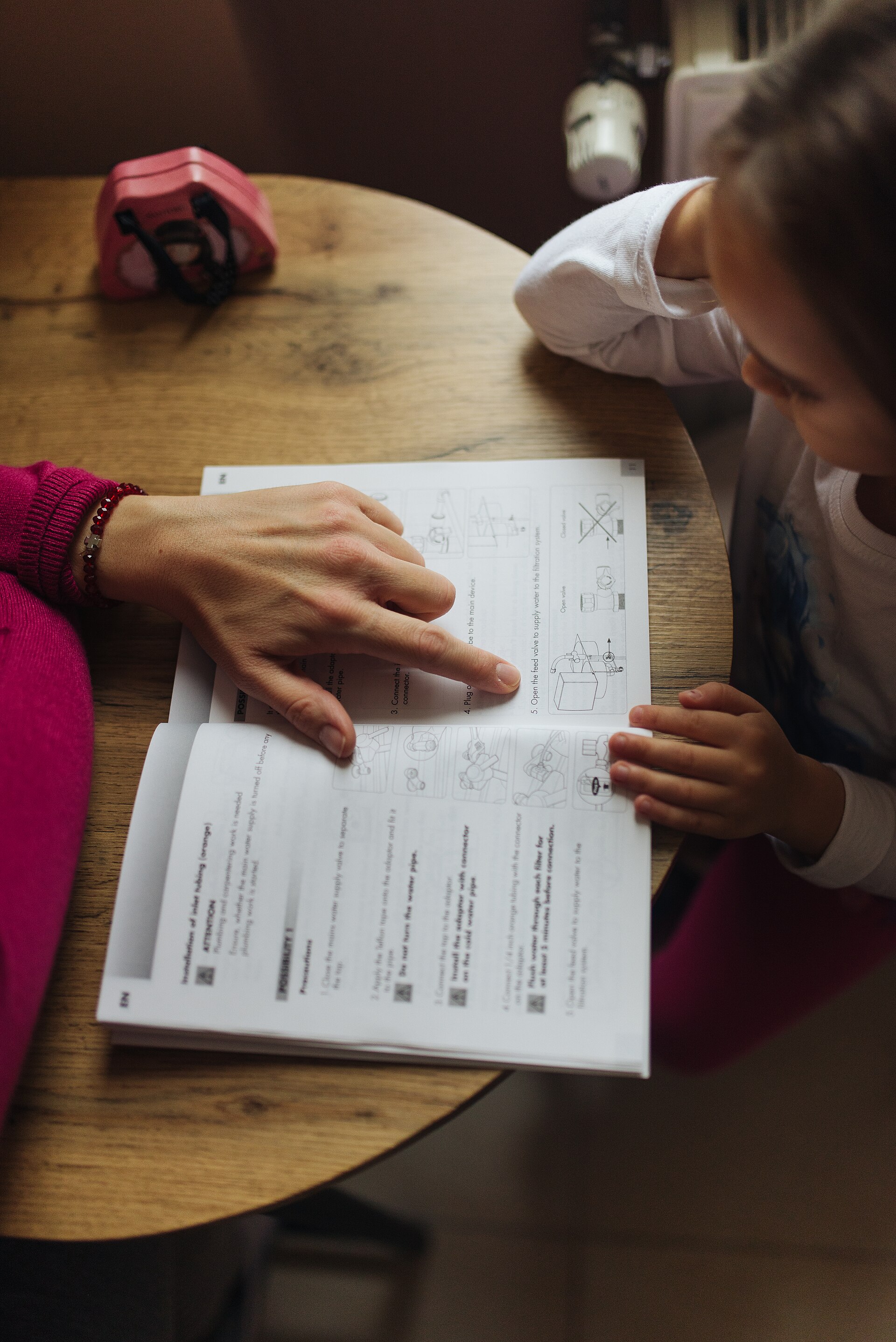 A parent helping a child with schoolwork at a table