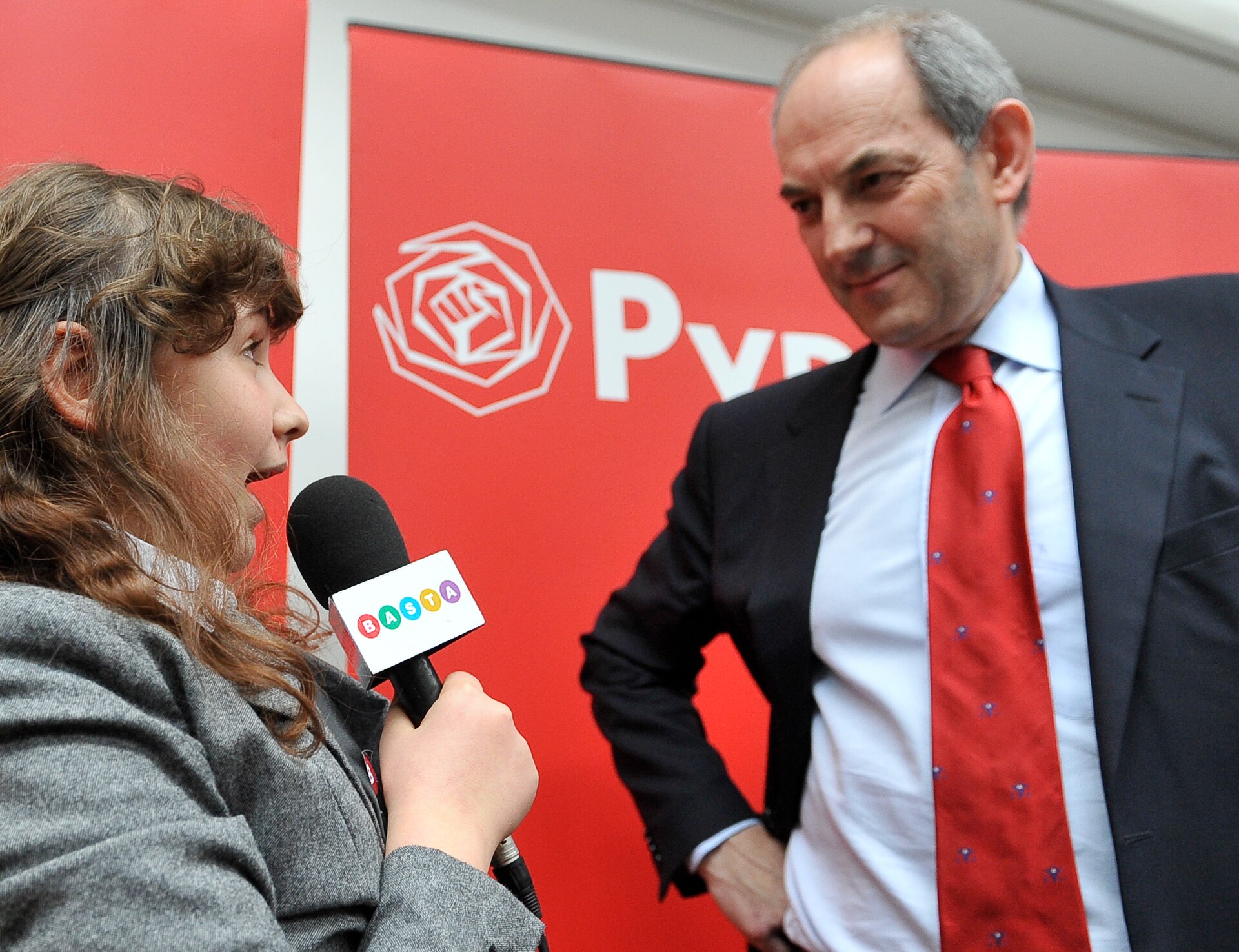 An interviewer holding a microphone to a man in a suit