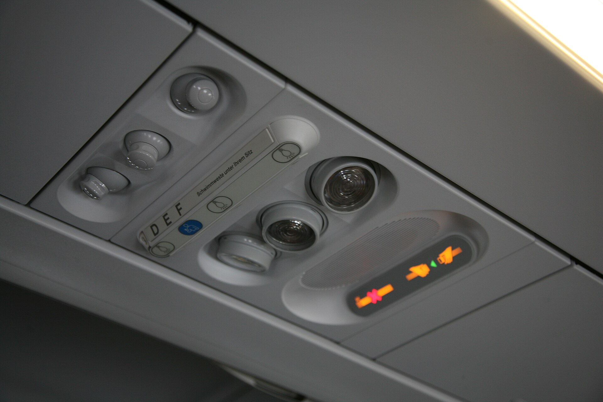 Overhead panel with reading lights and air vents above airplane seats