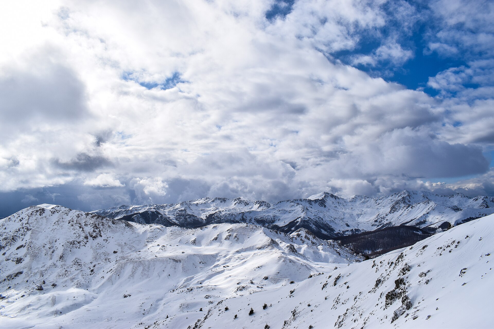Snow-covered mountain ridges under cloud