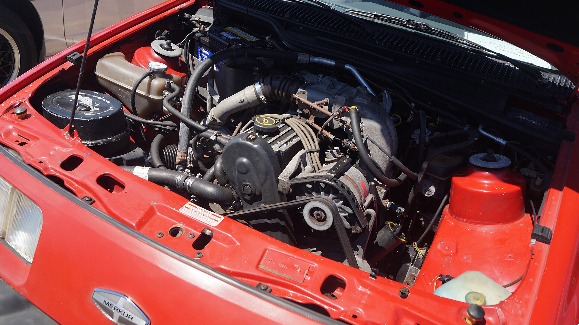 A car engine bay showing the engine and hoses