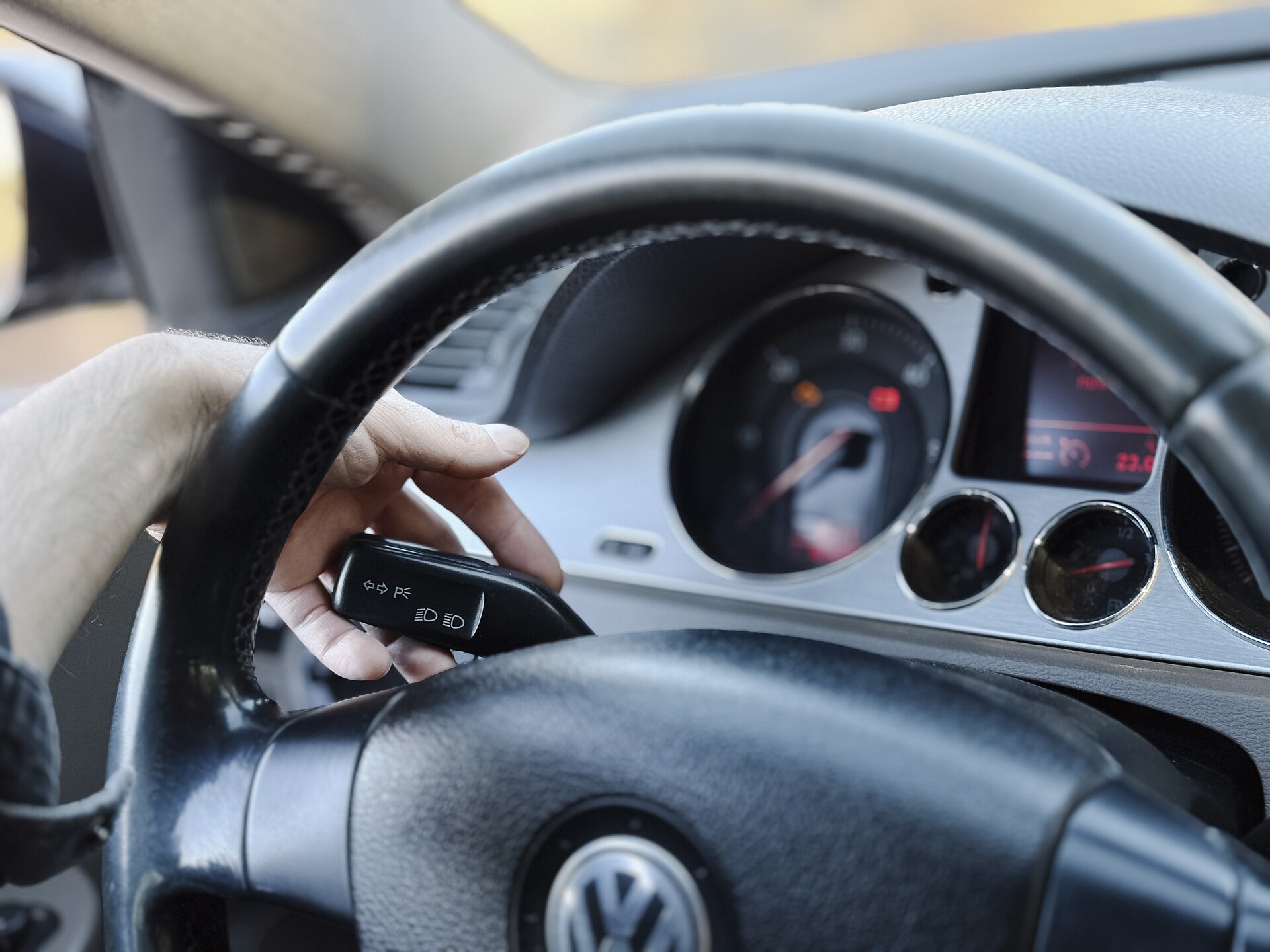 A driver holding a car key near the steering wheel while starting the engine