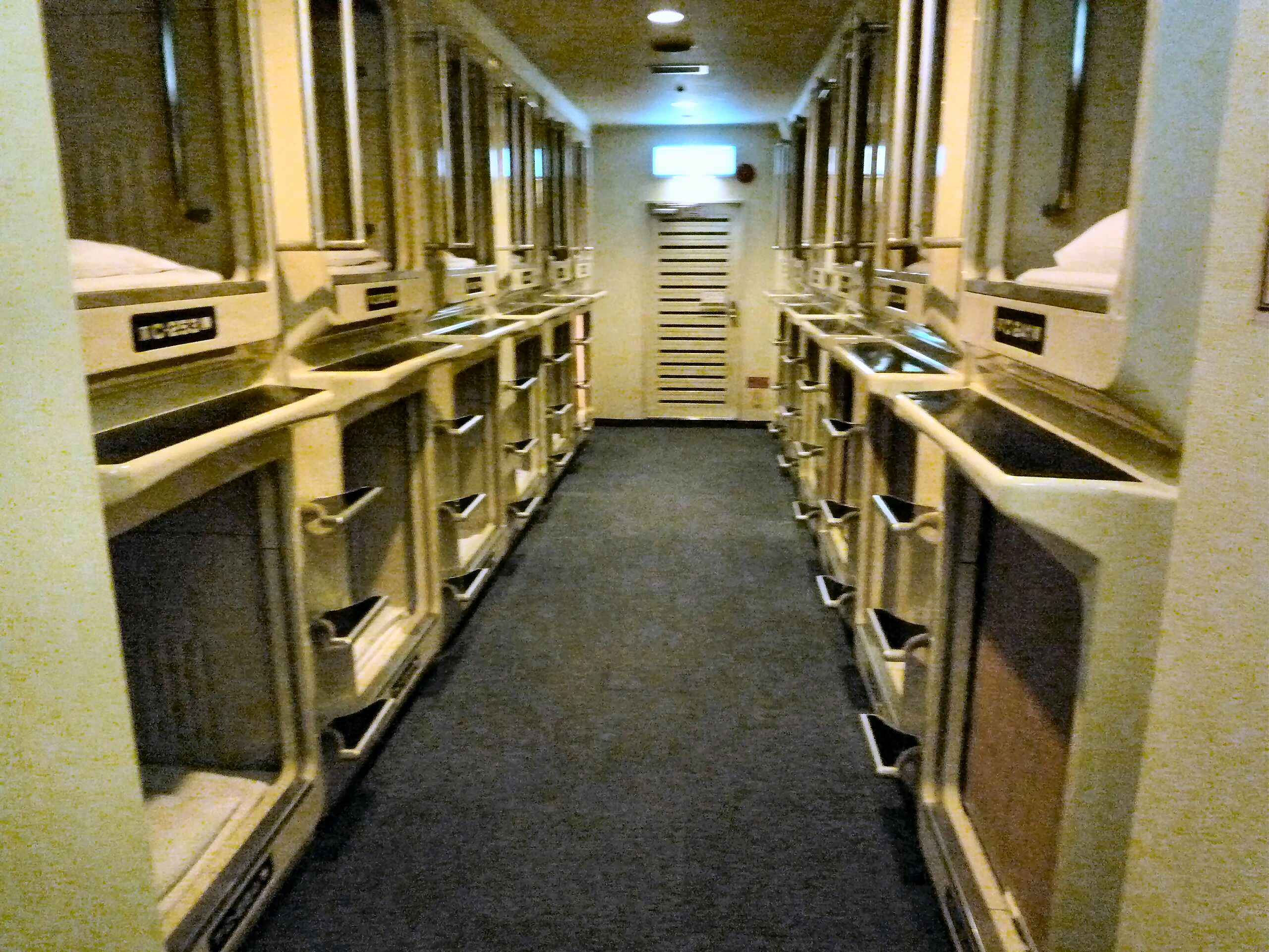 Capsule hotel corridor with rows of pods