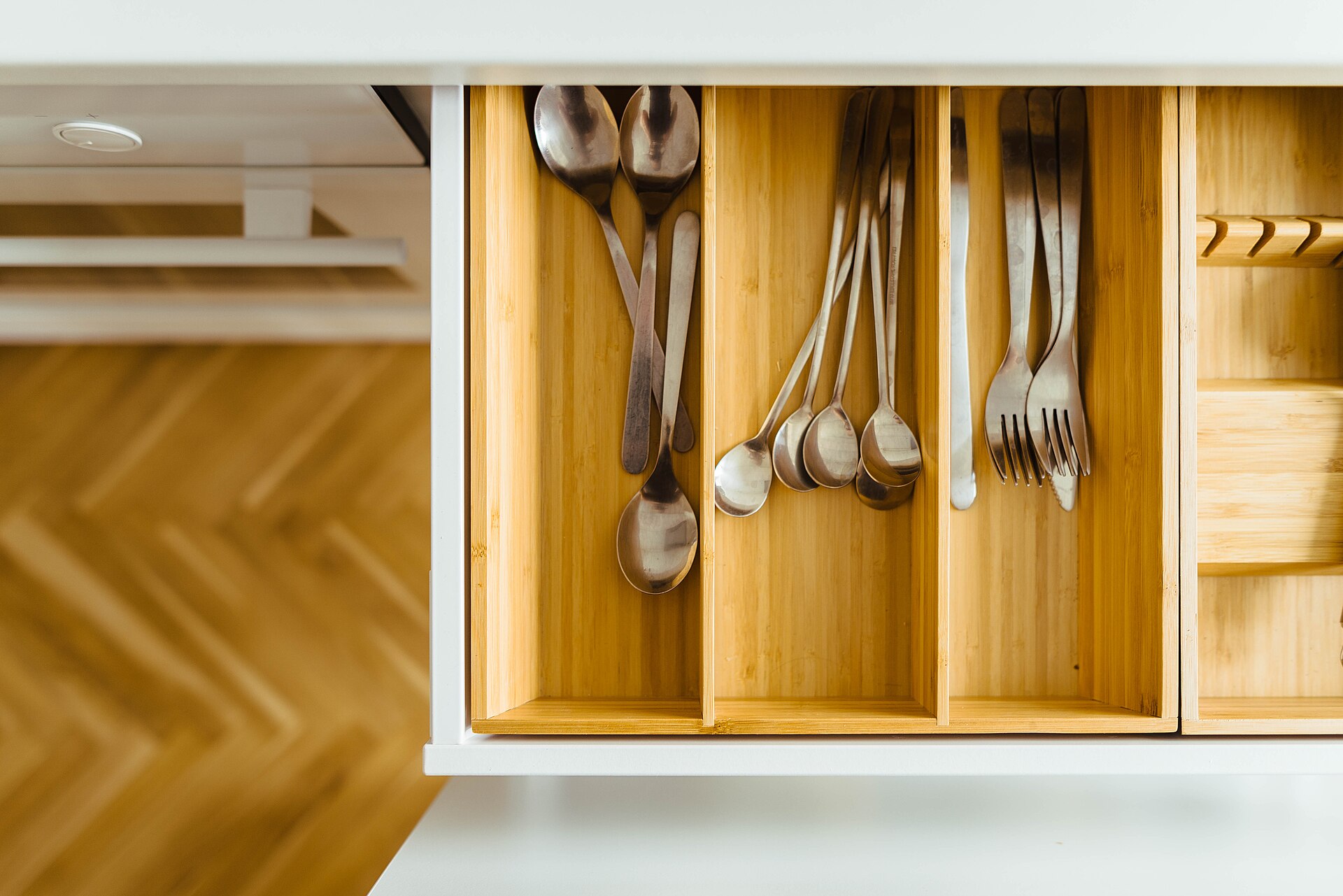 An open kitchen drawer with a wooden cutlery organiser