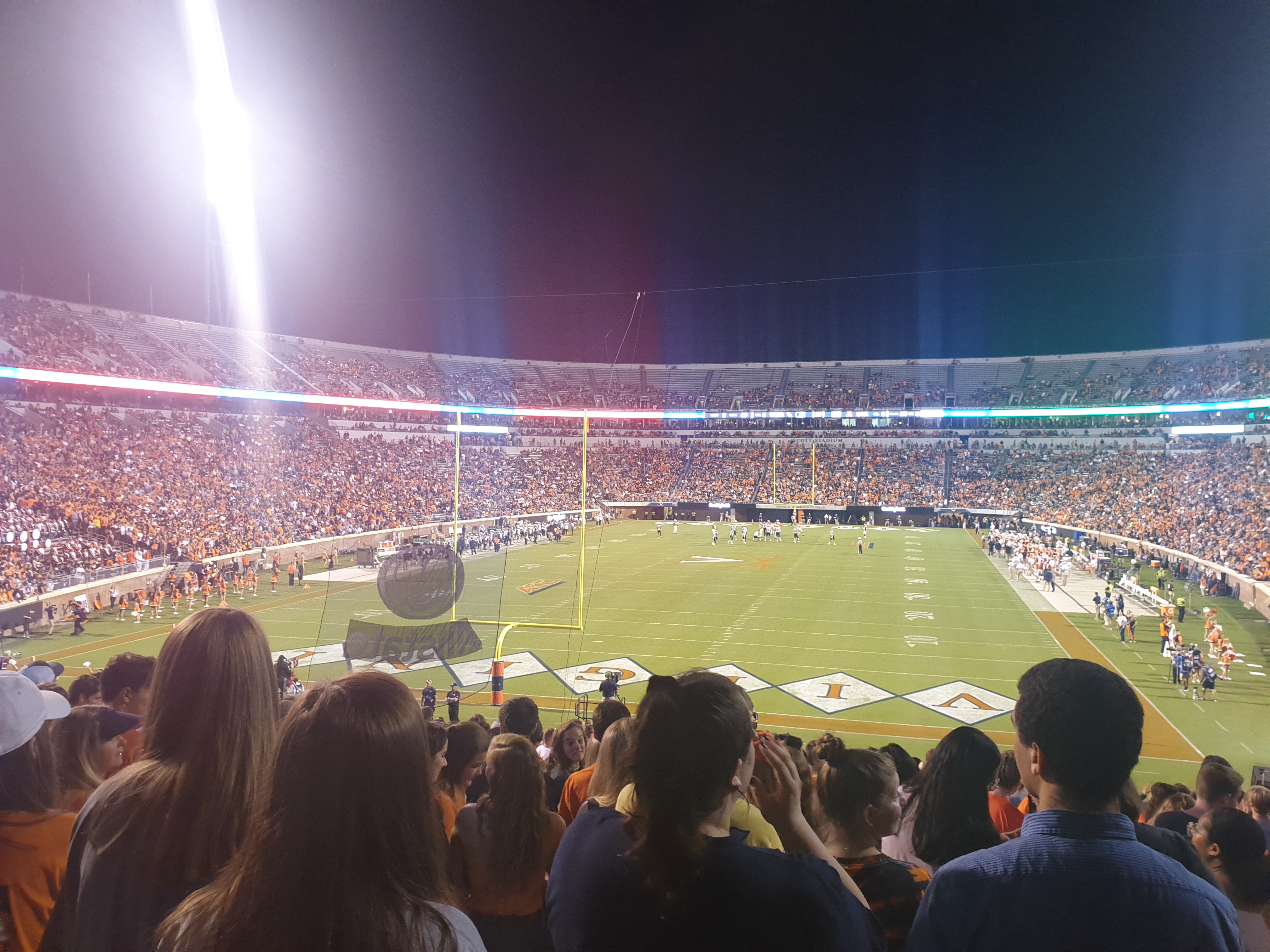 College football action under the lights at a packed stadium