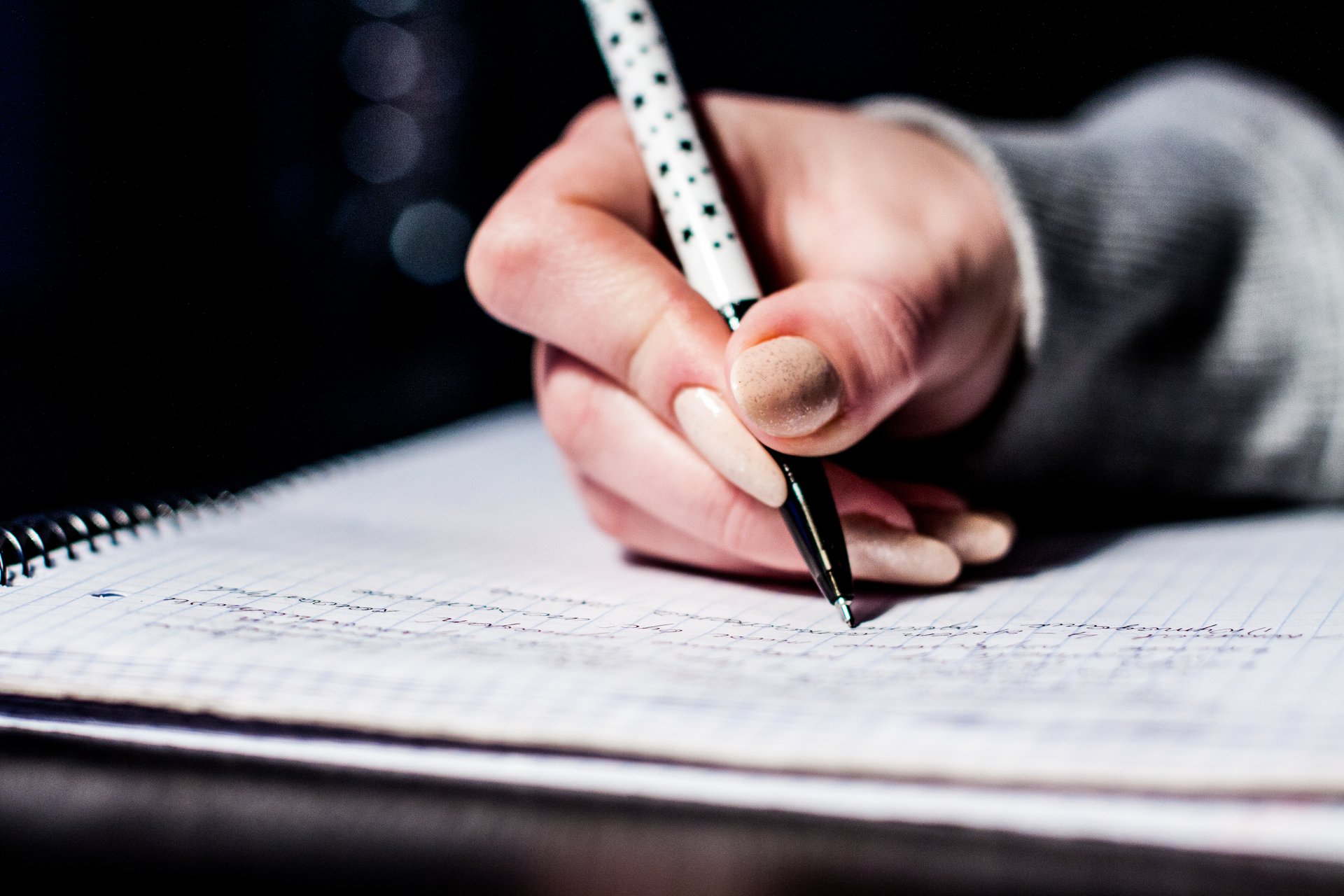 A student writes notes by hand in a notebook