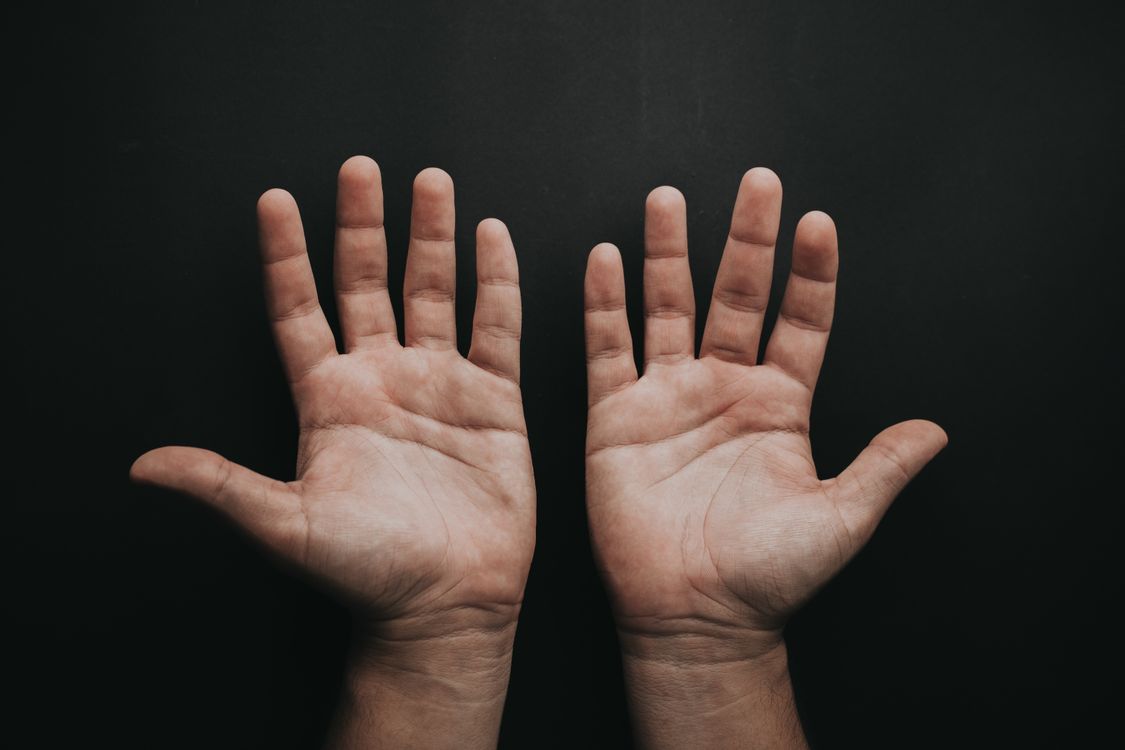 Two open hands with palms facing up against a dark background