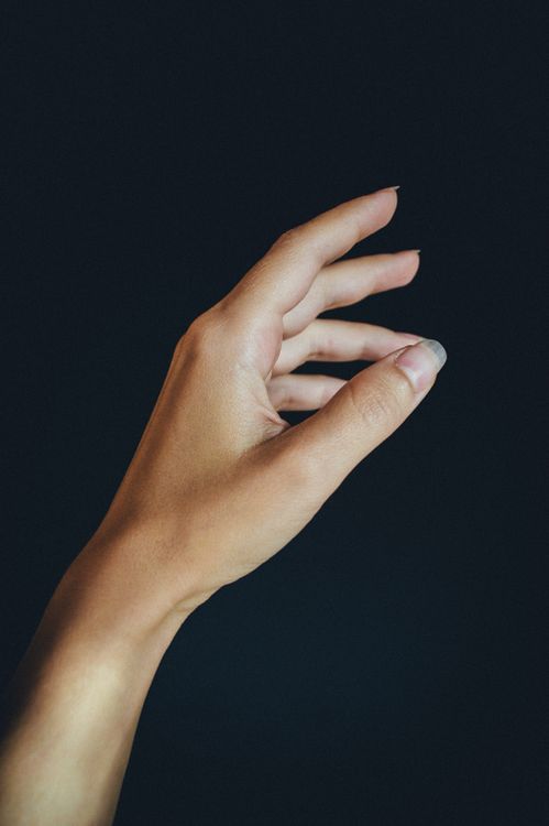 A hand with fingers relaxed against a dark background