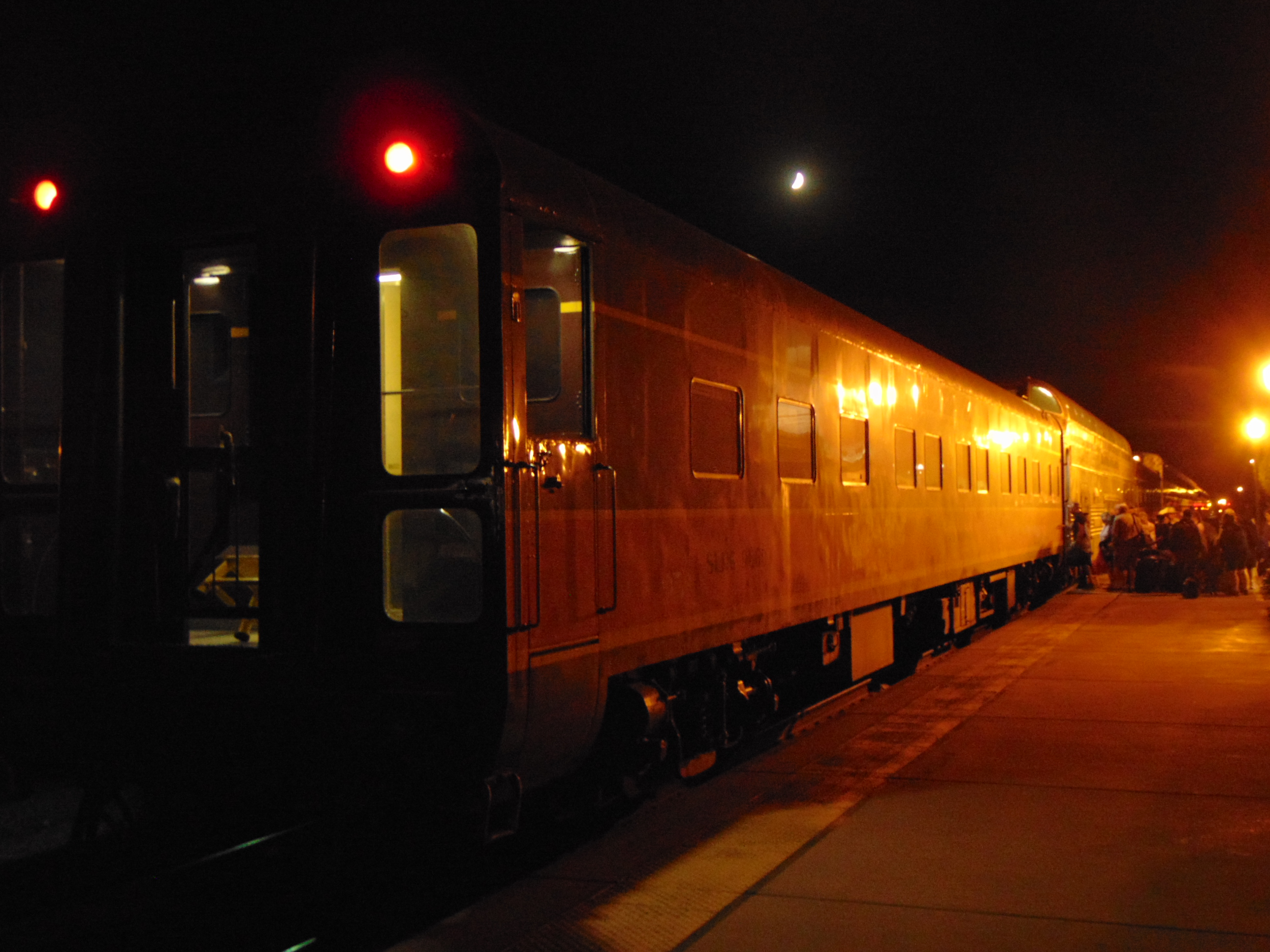 Passengers wait on a station platform beside a train
