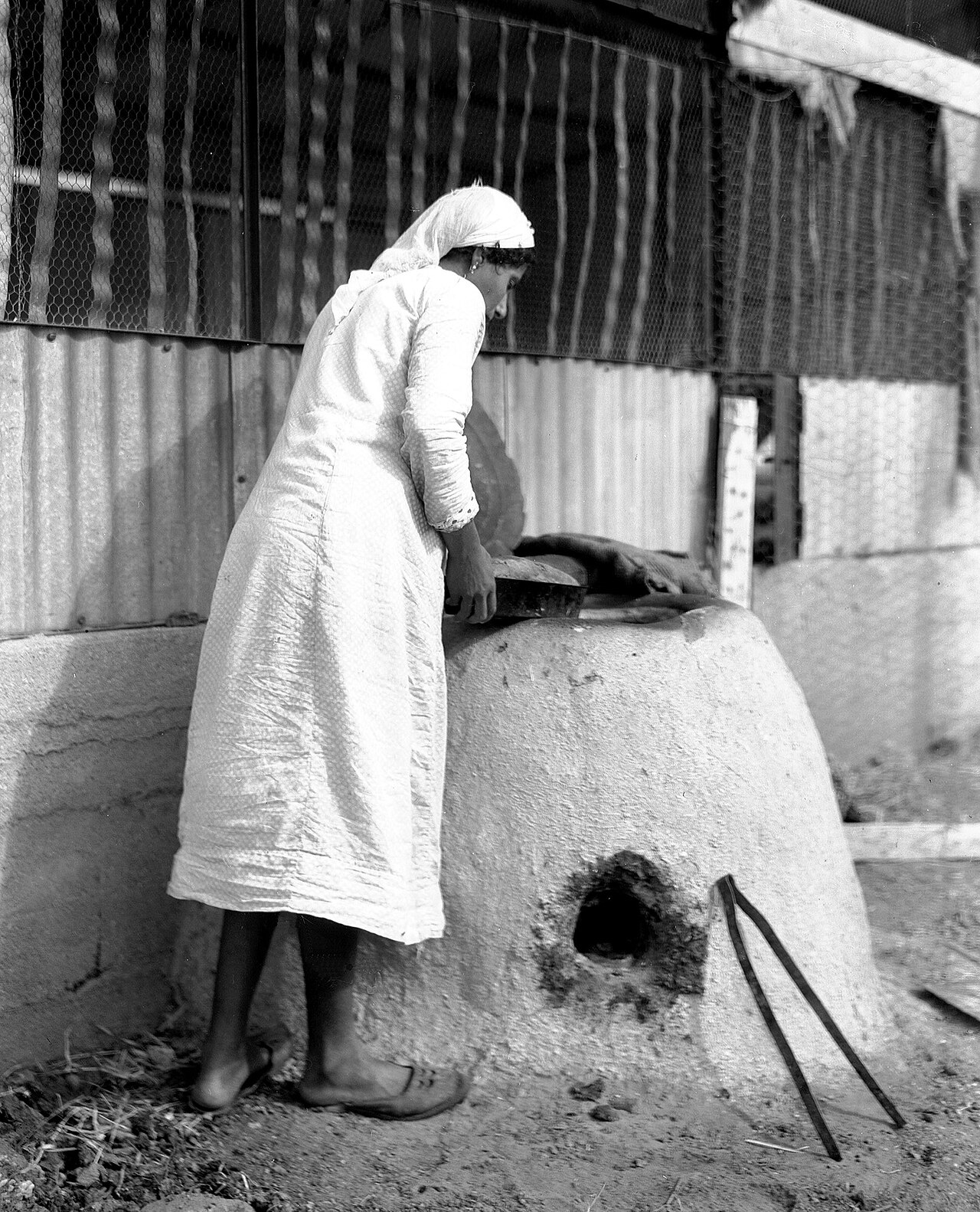 A woman placing bread into a traditional clay oven