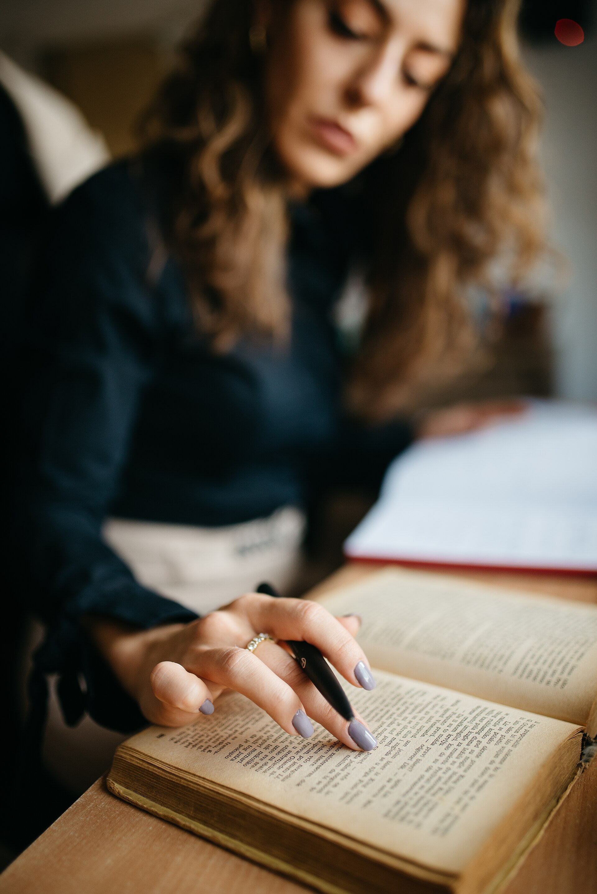 A young woman reading a book and taking notes at a study desk