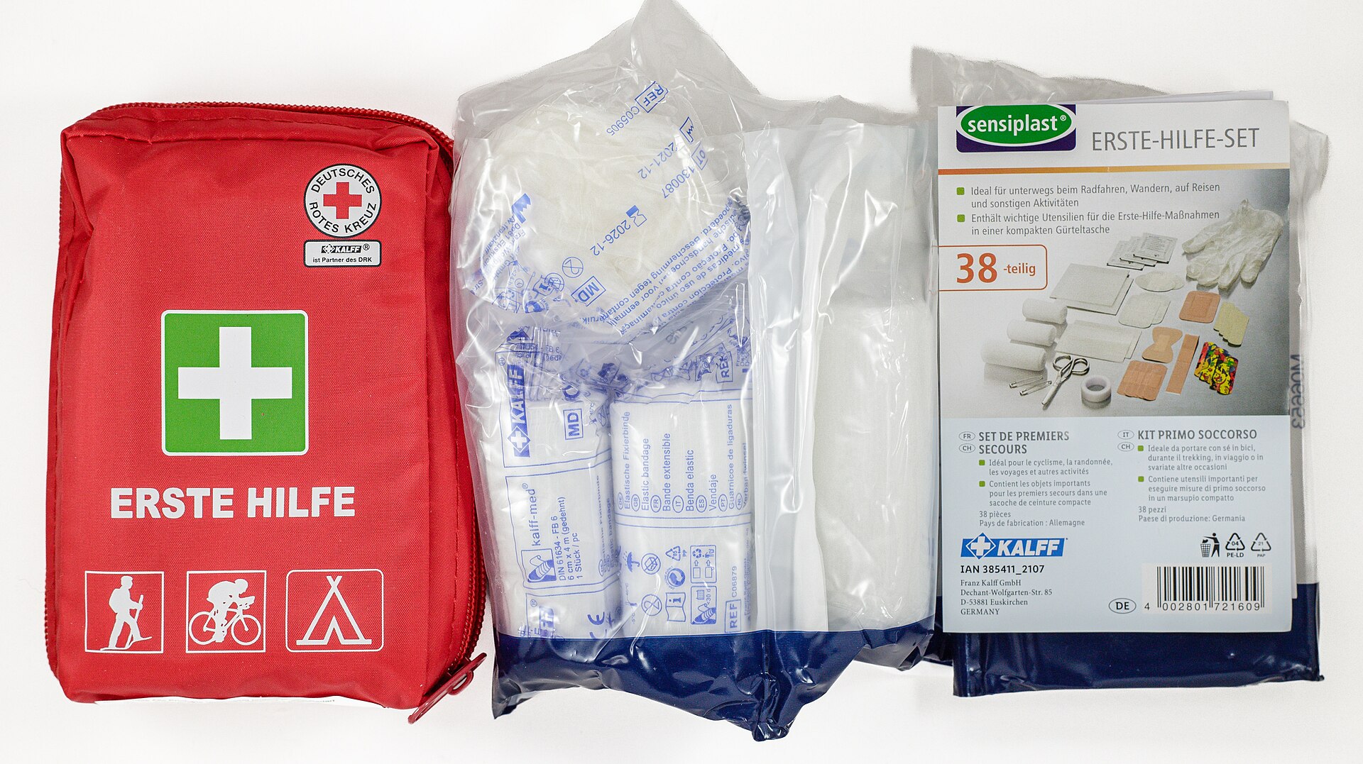A red first aid pouch beside sealed bandage packs and a first aid kit box