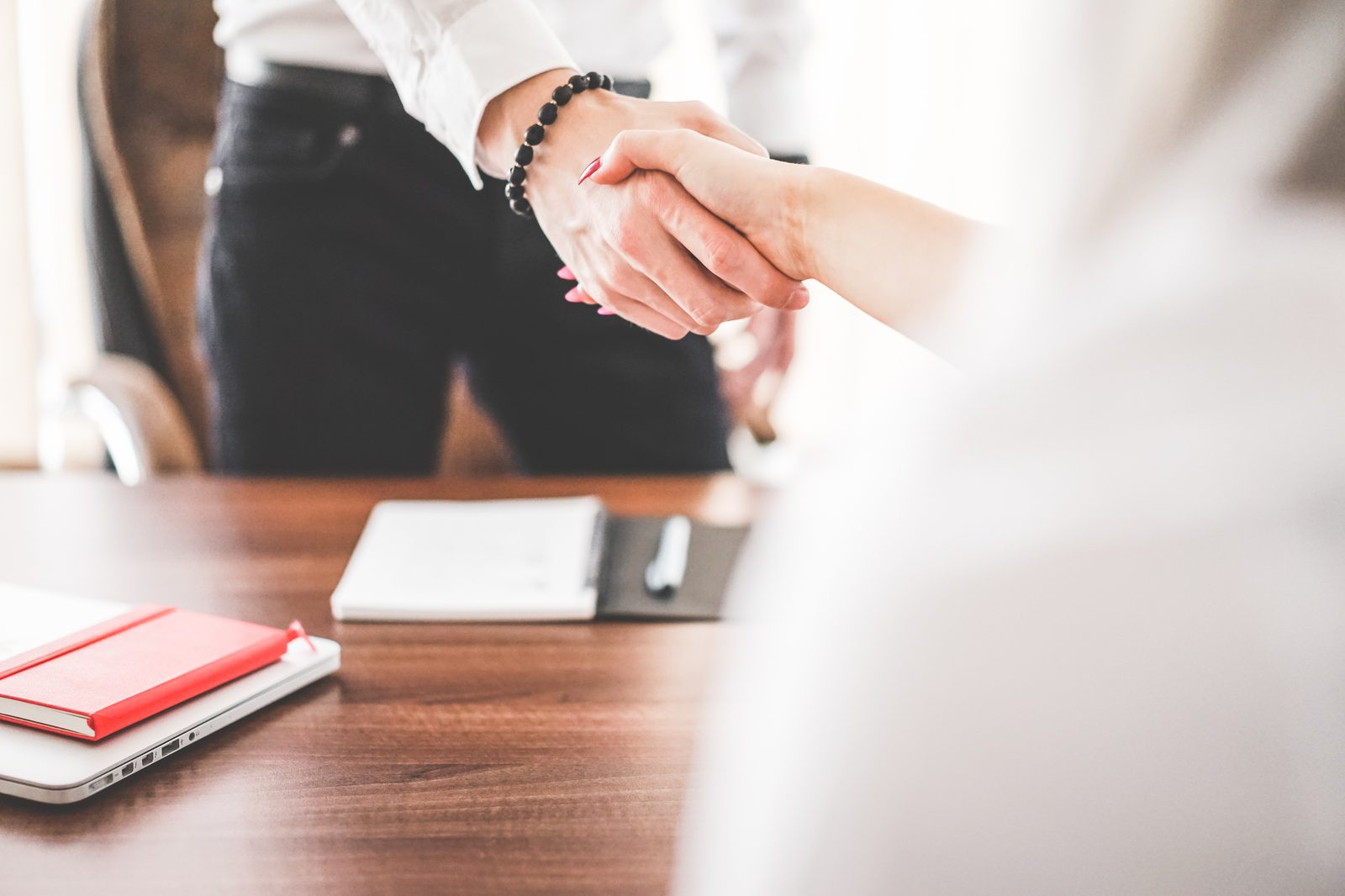 Two colleagues shaking hands in an office after a meeting