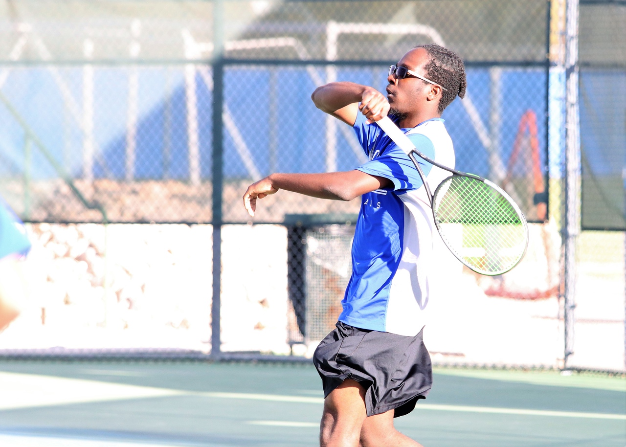 A tennis player returns a serve during a match