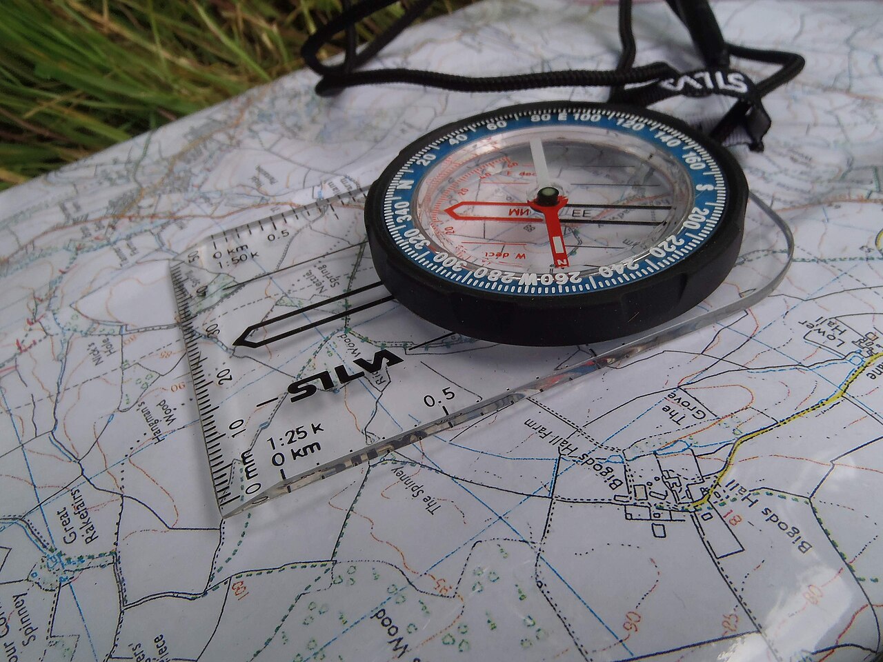 A baseplate compass resting on a folded topographic map