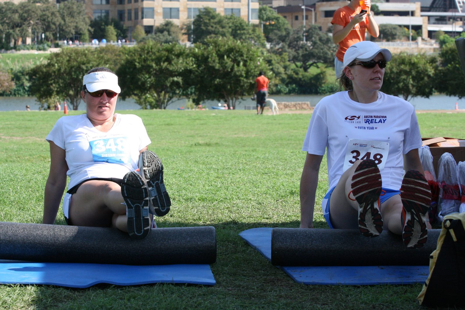 Two runners foam rolling their legs on mats after a race