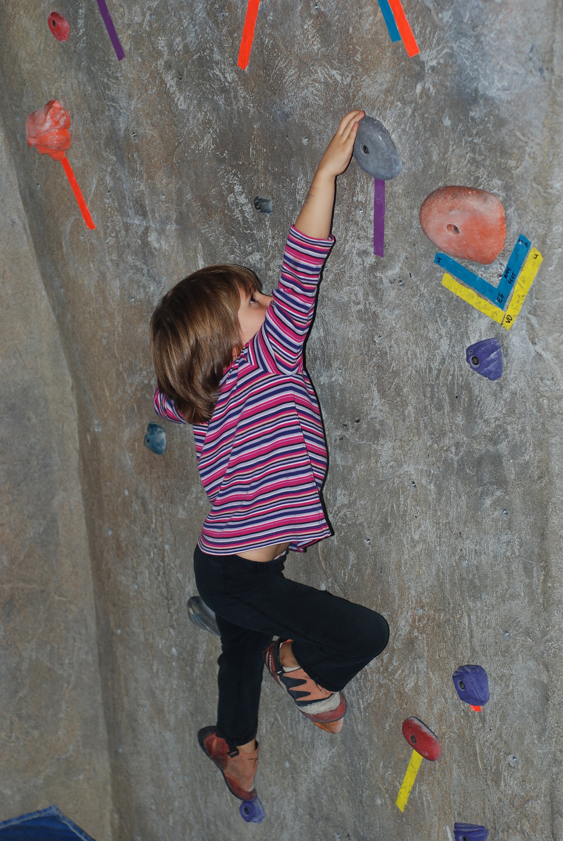 A young climber on a taped indoor bouldering route