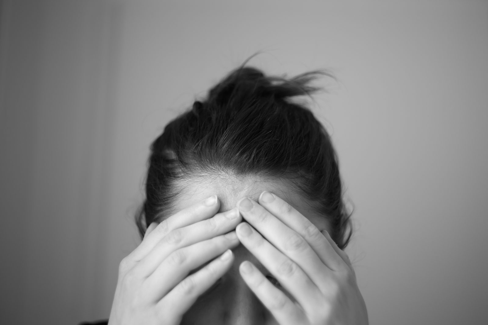 A person pressing their fingers to their forehead with eyes closed