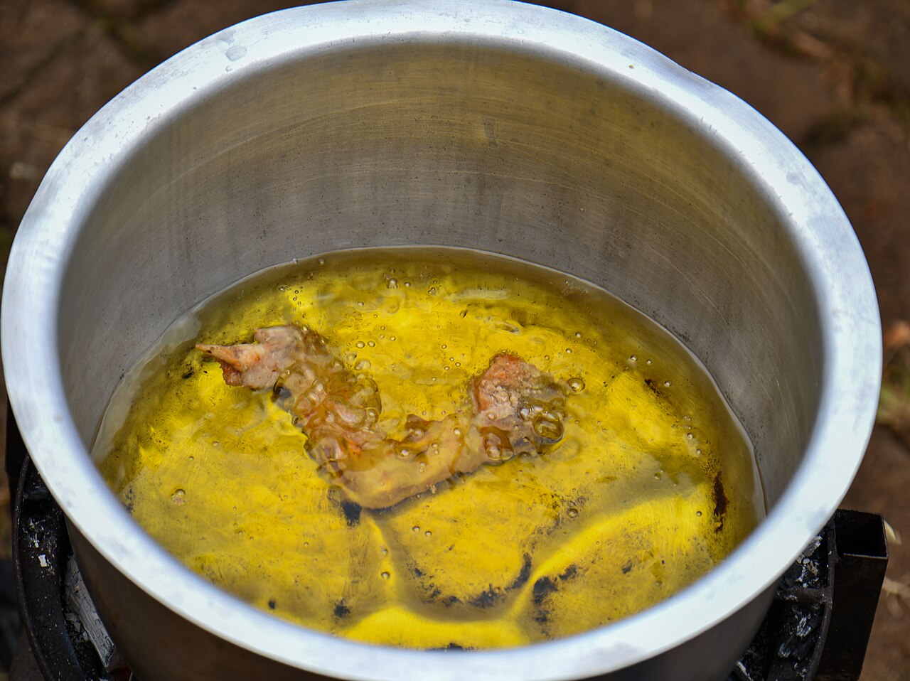 Cooking oil bubbles as chicken deep-fries in a pot