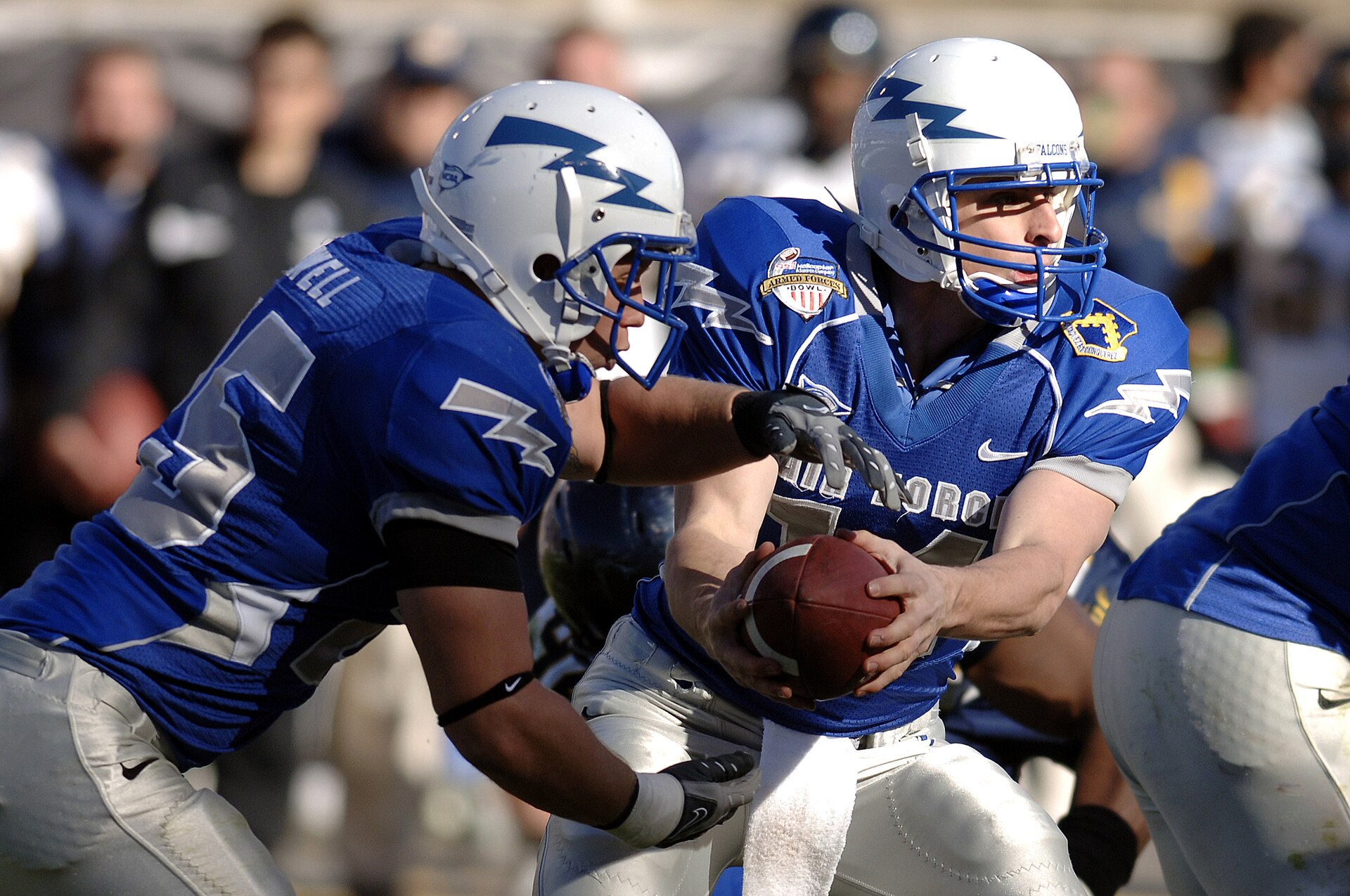 A quarterback hands the ball to a teammate on a running play